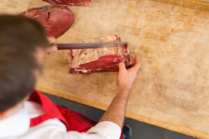 Butcher Cutting Meat At Counter high angle, custom meat cutting near Peoria IL, meat cutting Peoria IL, meat processor Peoria IL, custom meat processor Peoria IL, USDA meat processing Peoria IL, beef processing Peoria IL, pork processing Peoria IL, custom butchering Peoria IL, meat packaging Peoria IL, meat fabrication Peoria IL, butcher services Peoria IL, meat processing near Peoria IL, livestock processing Peoria IL, custom meat packaging Peoria IL, restaurant meat supplier Peoria IL, wholesale meat processing Peoria IL, meat cutting services Peoria IL, meat processing Canton IL, USDA butcher Peoria IL, custom meat fabrication Peoria IL