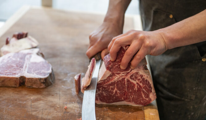 Close-up of butcher slicing raw beef for Pekin IL customer
